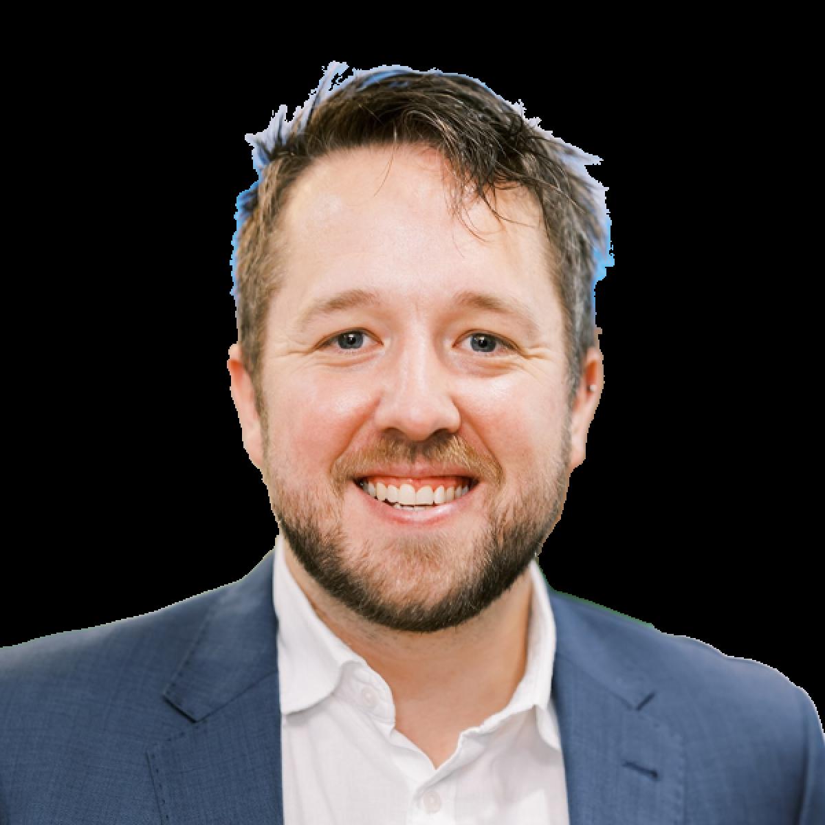 Professional headshot of smiling male doctor in navy suit jacket and white shirt against white background